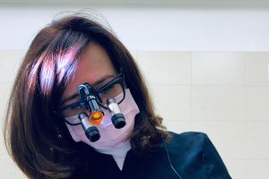 Brown-haired dental hygienist wears glasses and a face mask